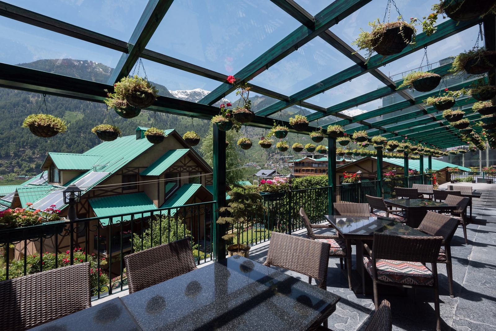 Glass-roofed terrace with hanging baskets and mountain views